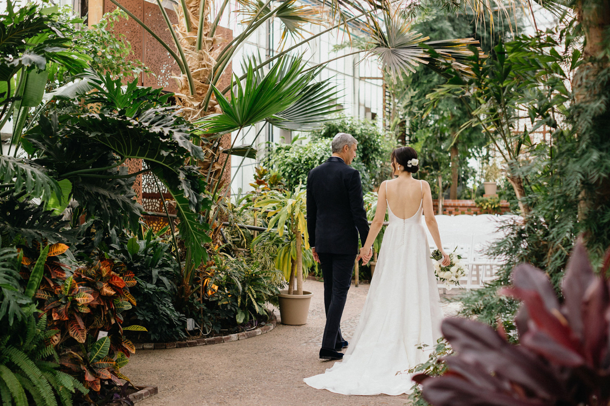 Bride and groom holding hands as they walk through the botanical gardens at the Fairmount Park Horticulture Center in Philly.