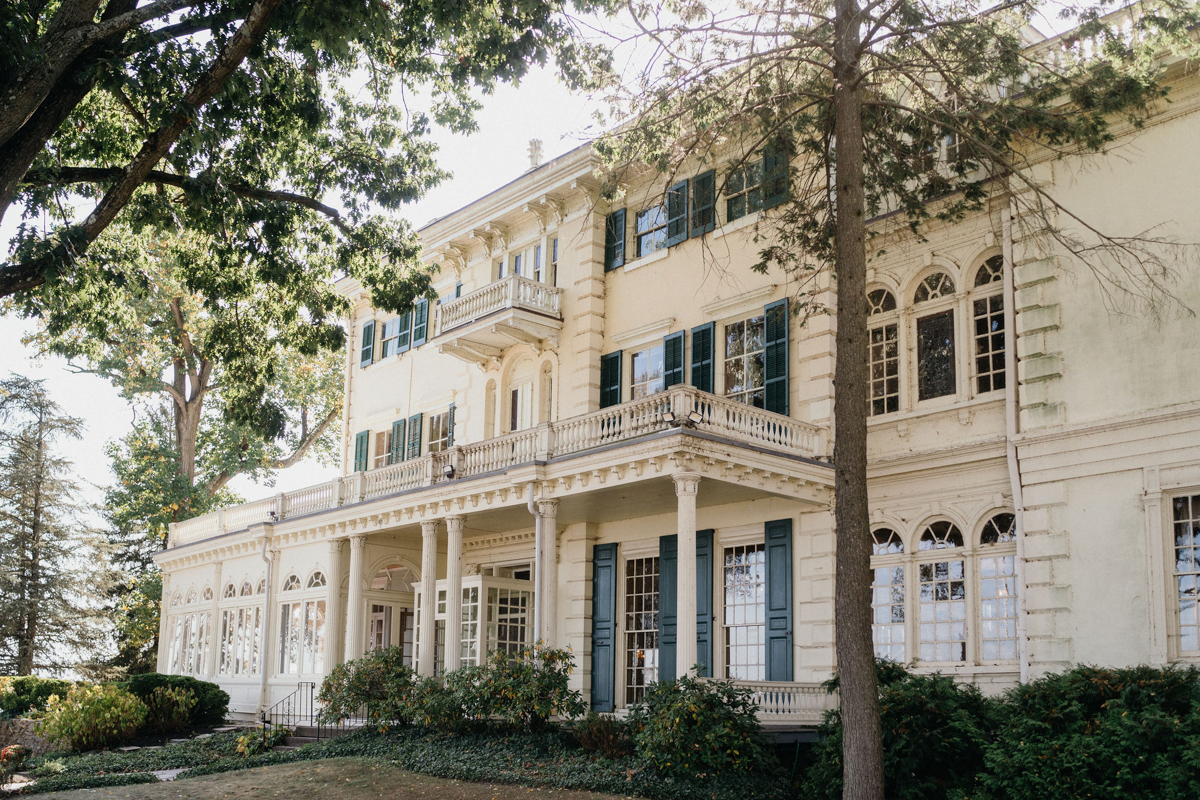 White mansion estate wedding venue in Philadelphia with green shutters and sunrooms.