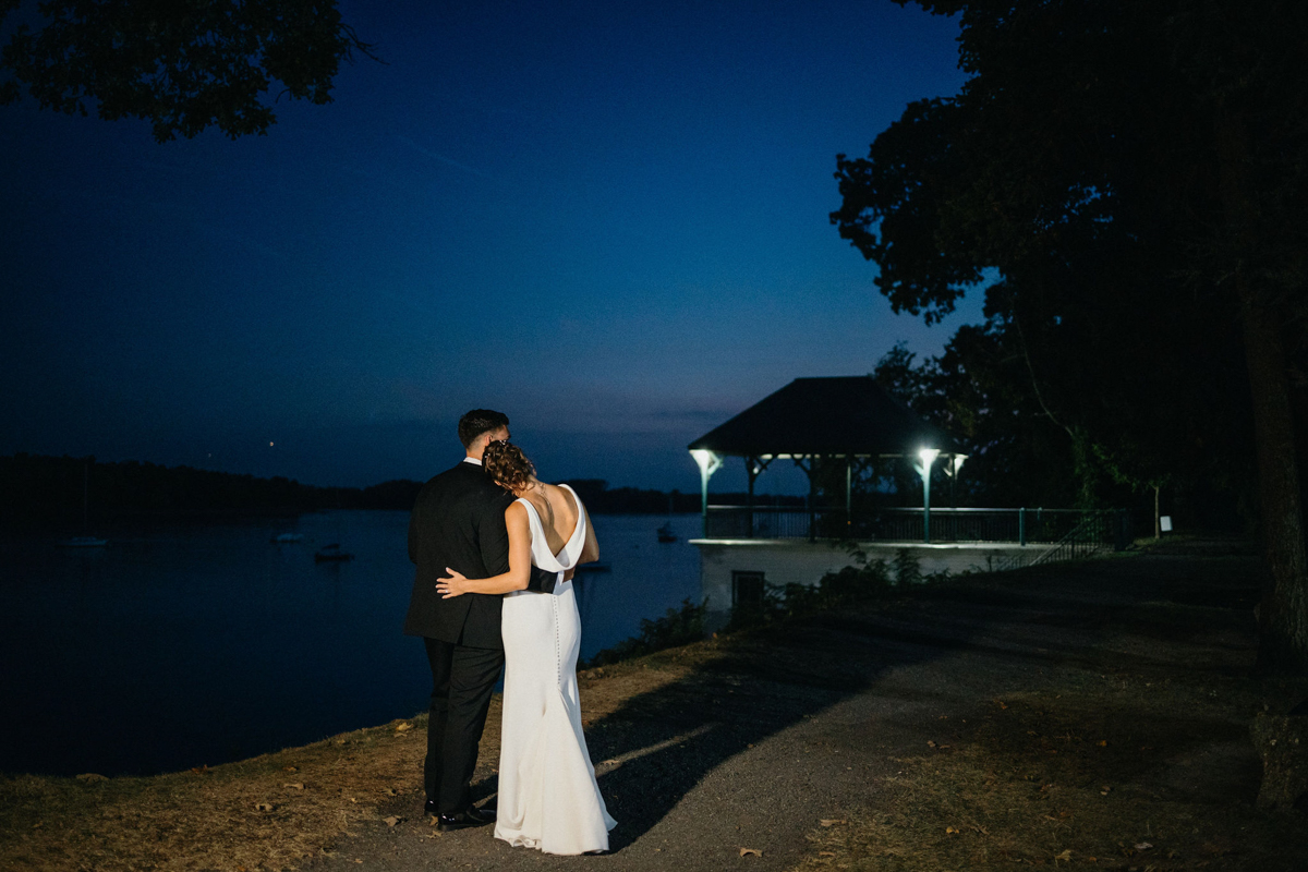 Nighttime wedding portrait of bride and groom on the waterfront.