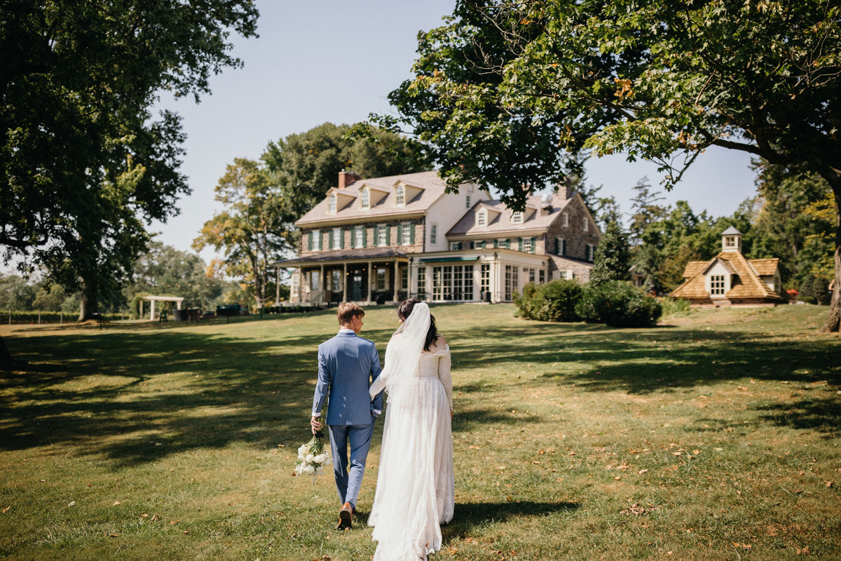 Bride and groom walk through the field in front of the Inn at Grace Winery