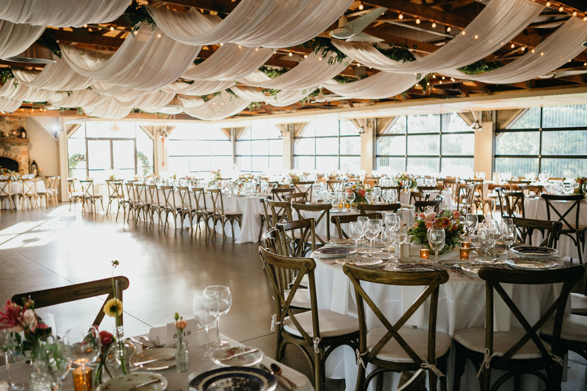 Indoor rustic reception space with white drapery on the ceiling.