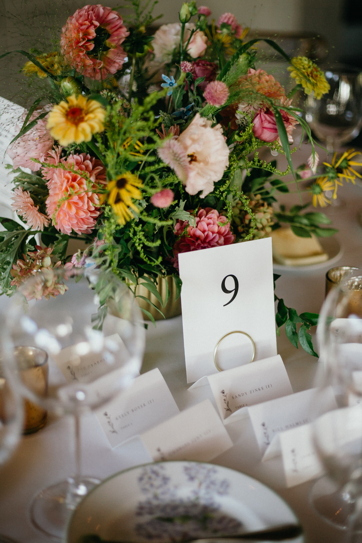 Pink and yellow floral pieces with table numbers and seating cards.