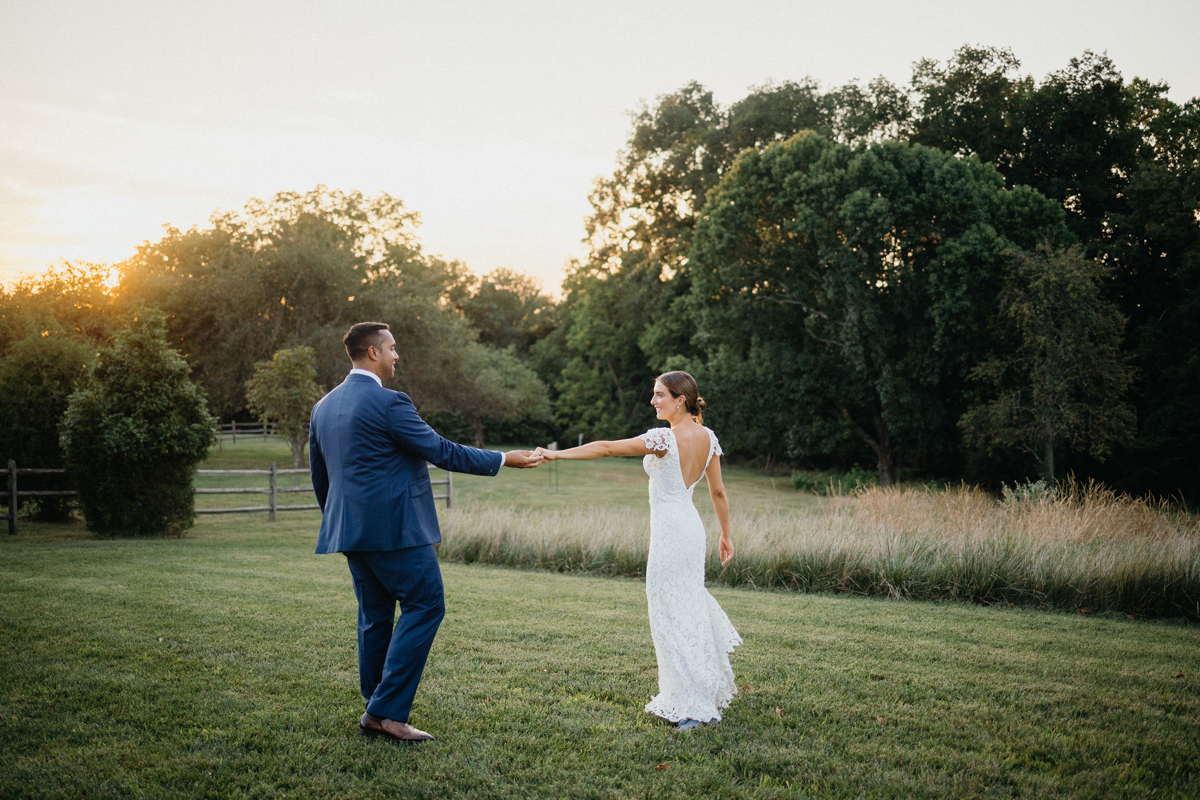 Bride and groom dancing candidly in a meadow behind their venue. 