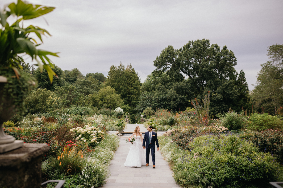 Wedding couple walking thru the Morris Arboretum gardens in Philadelphia, Pennsylvania.