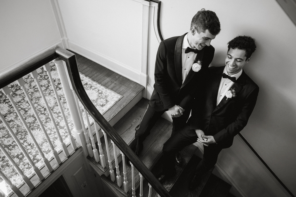 Candid photo of grooms on staircase at Philander Chase Knox Estate wedding.