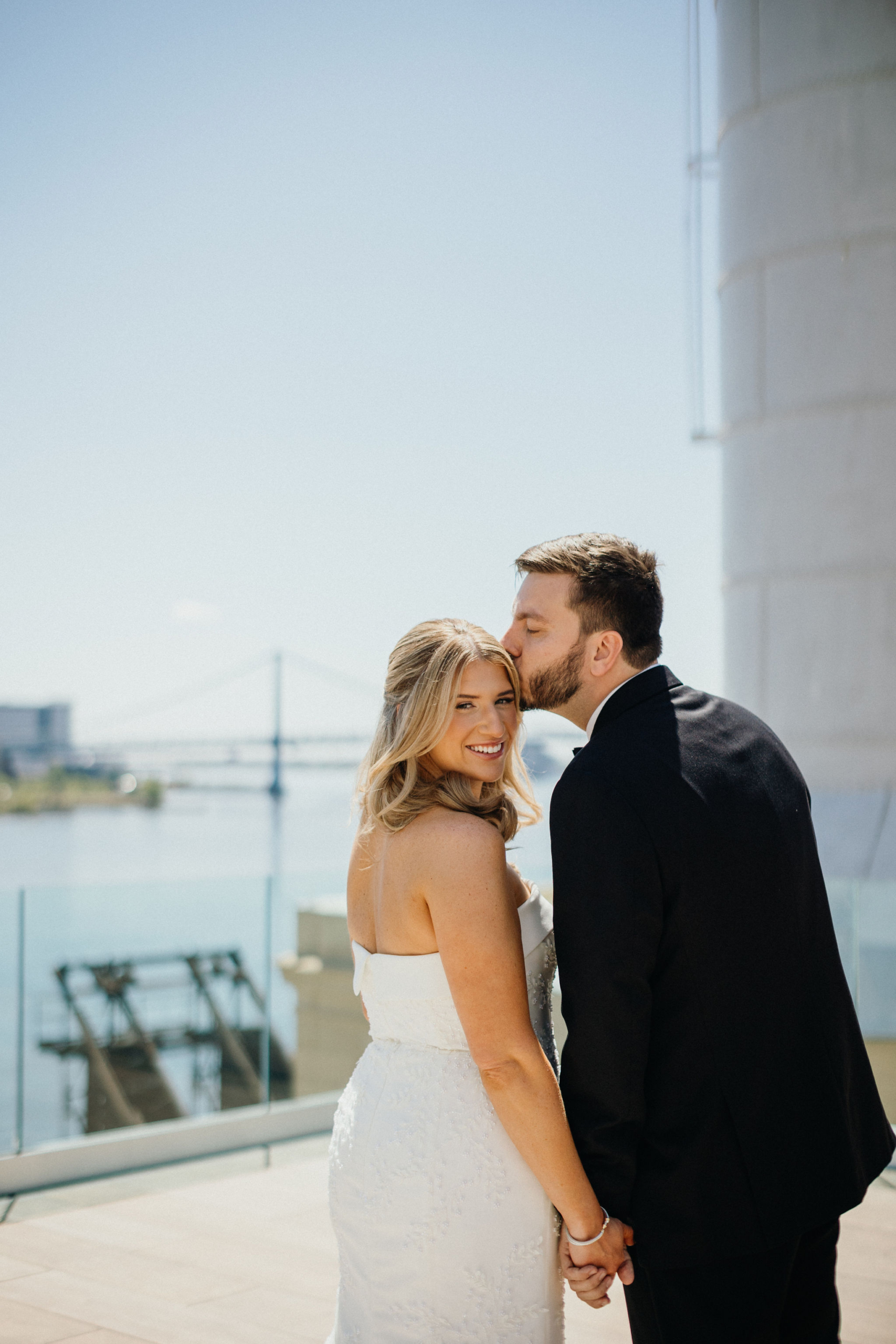 Windswept romance as the couple stands hand in hand above the city.