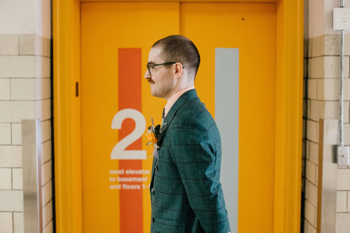 Groom waiting for first look before Bok wedding in front of an elevator door.