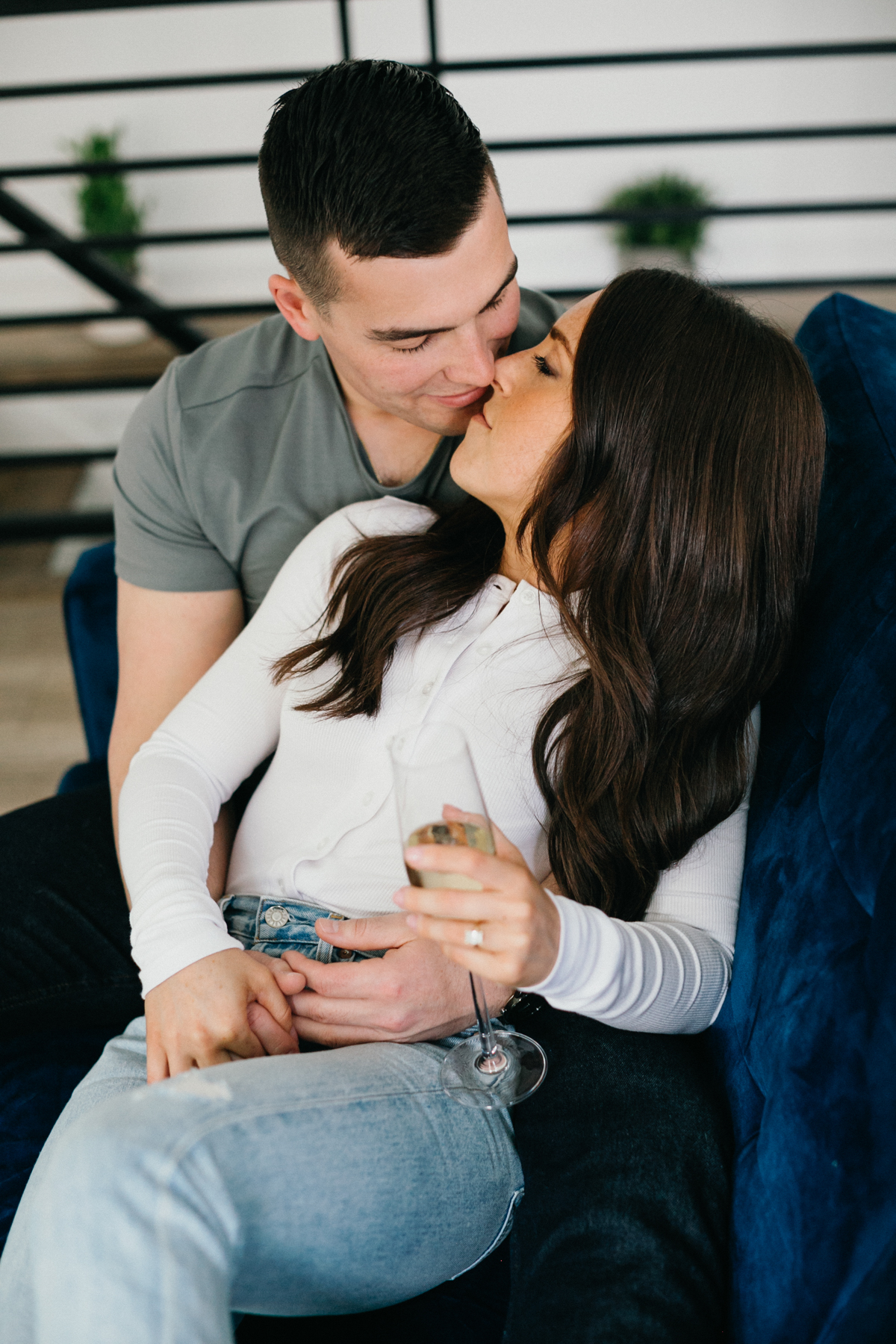  A couple relaxes on a cozy couch in a rented loft, sharing a quiet moment with natural light pouring through the windows.