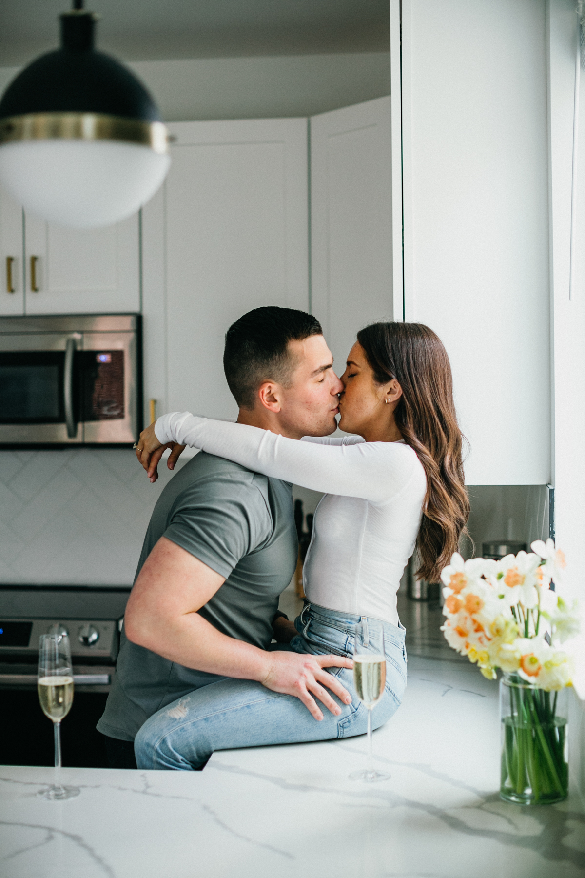 Couple kissing as woman sits playfully on the counter in an airbnb in Philly. 