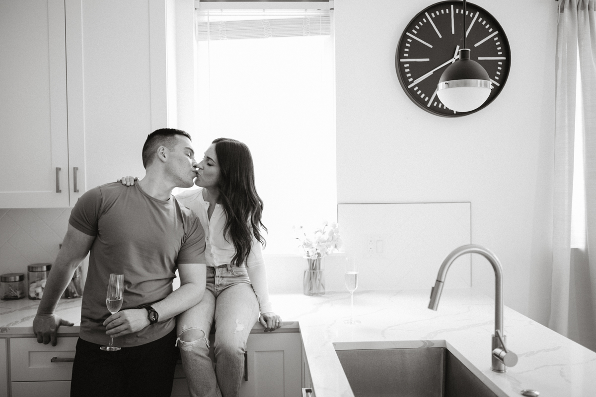 A couple stands near a large window in a rented apartment kitchen.