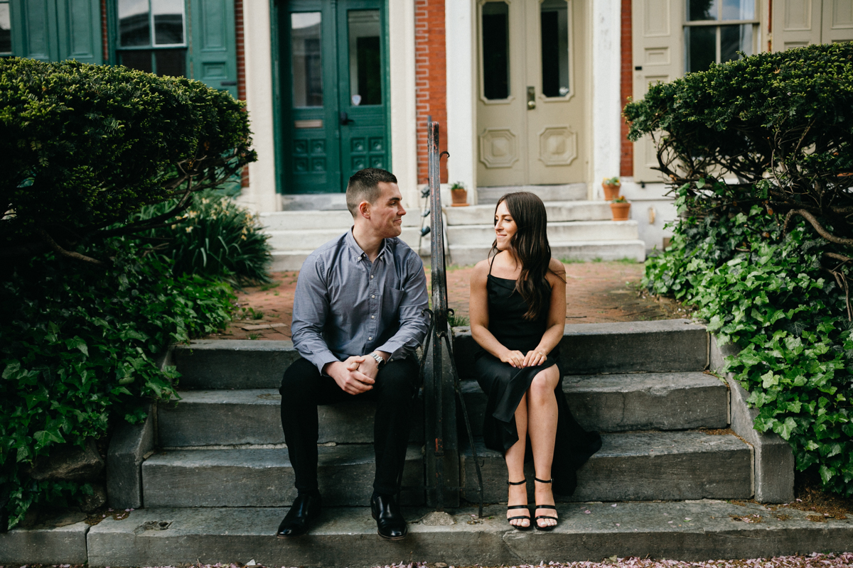 Couple sits out front of an airbnb in Philly for their engagement photos. 