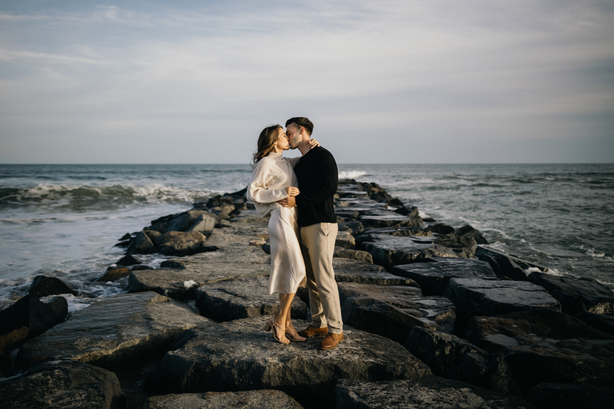 A pair of silhouettes against a golden sunset over the ocean, holding hands on a Jersey Shore beach.