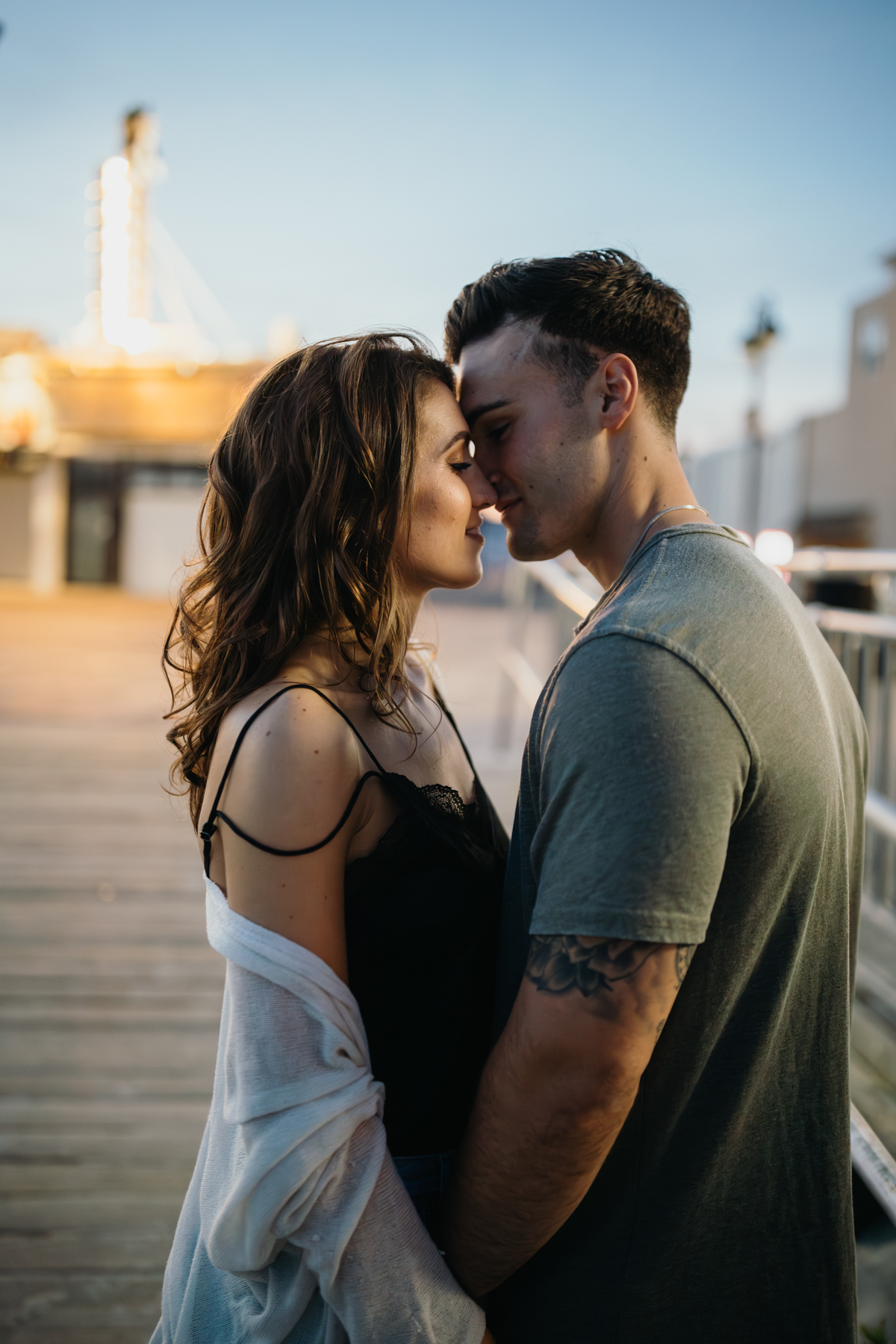 Romantic and sexy photo of couple looking at each other with the Jersey Shore boardwalk faintly visible.