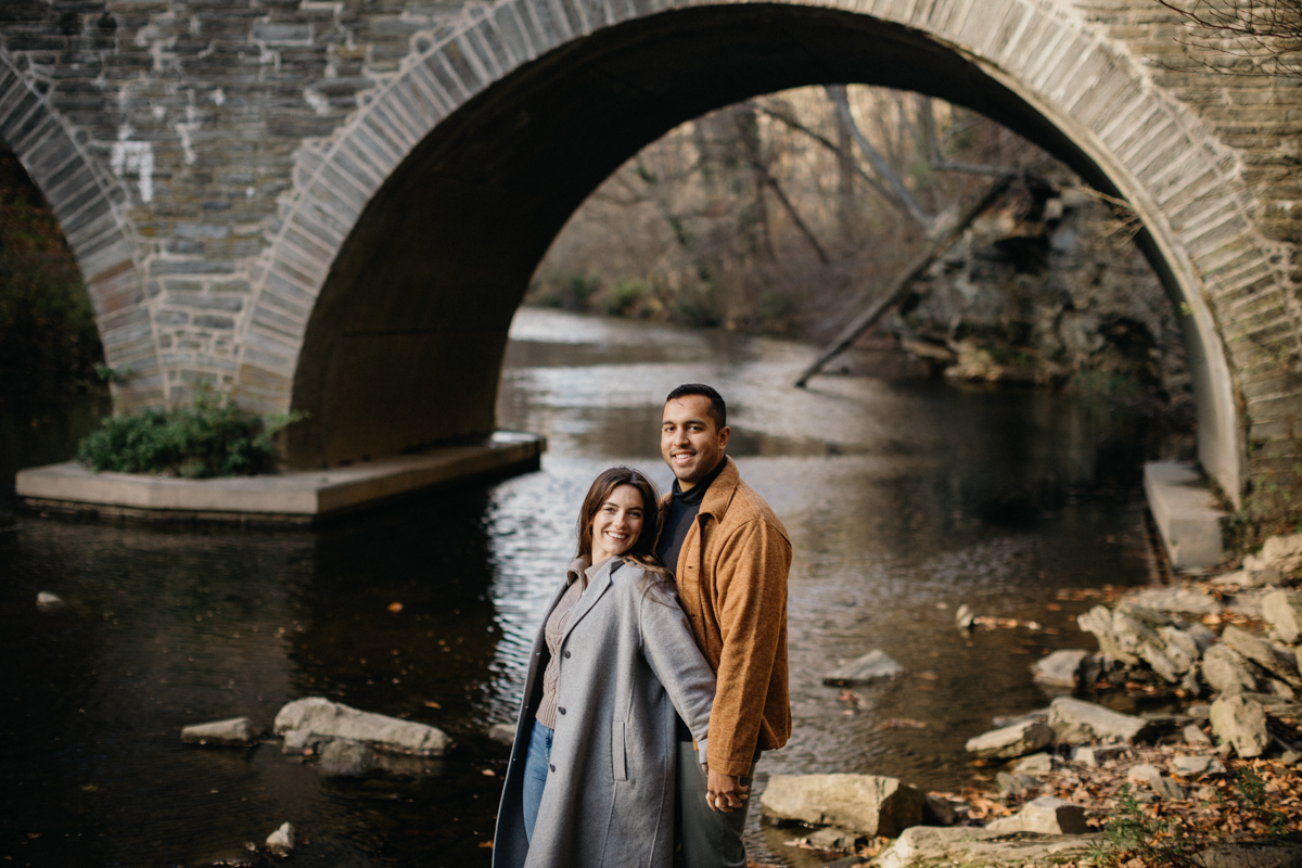 A couple walks hand in hand on a dirt path winding through the woods just outside Philadelphia.