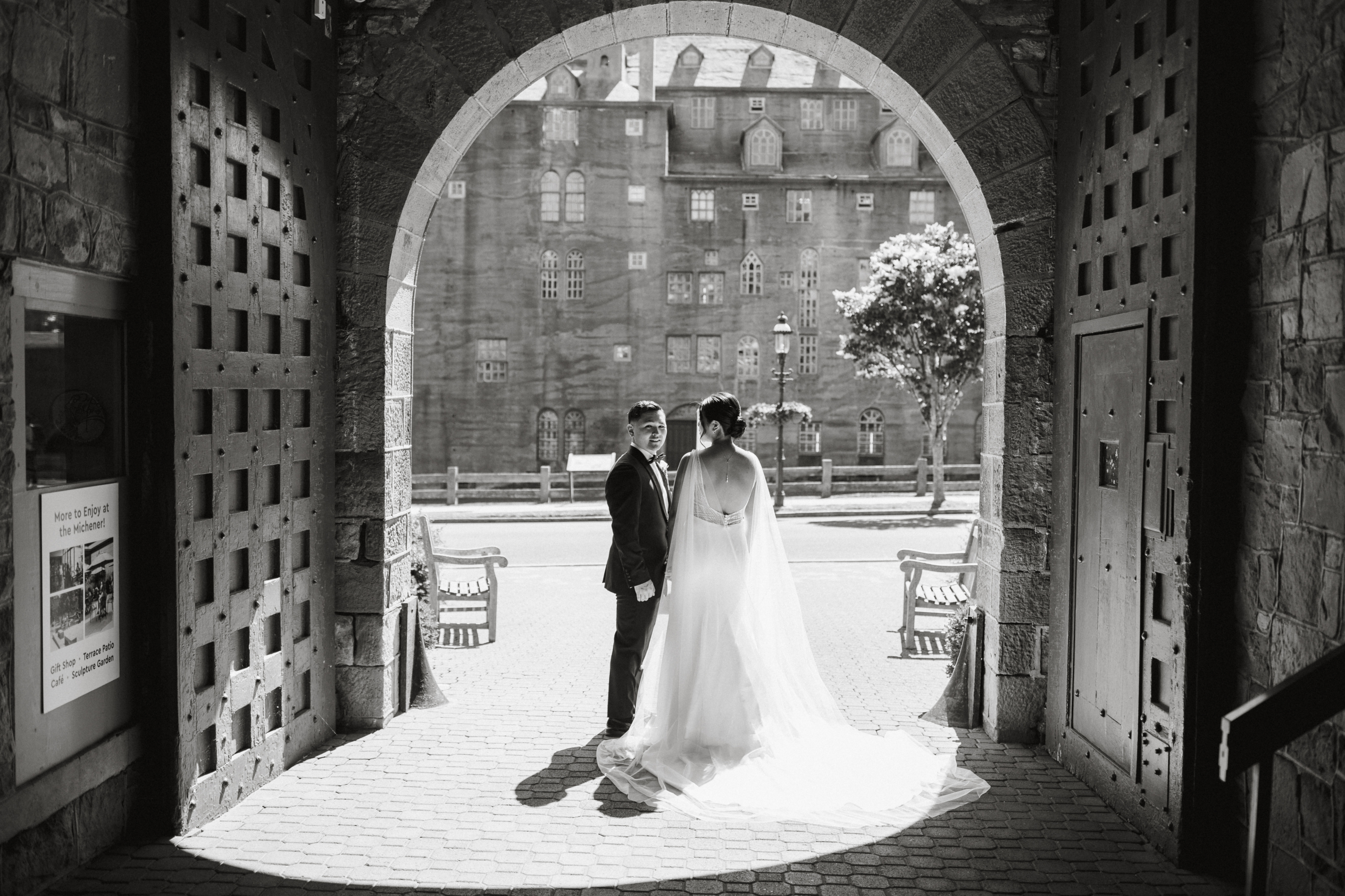 A couple stands together against the textured stone walls of the Michener Museum, sharing a quiet moment.