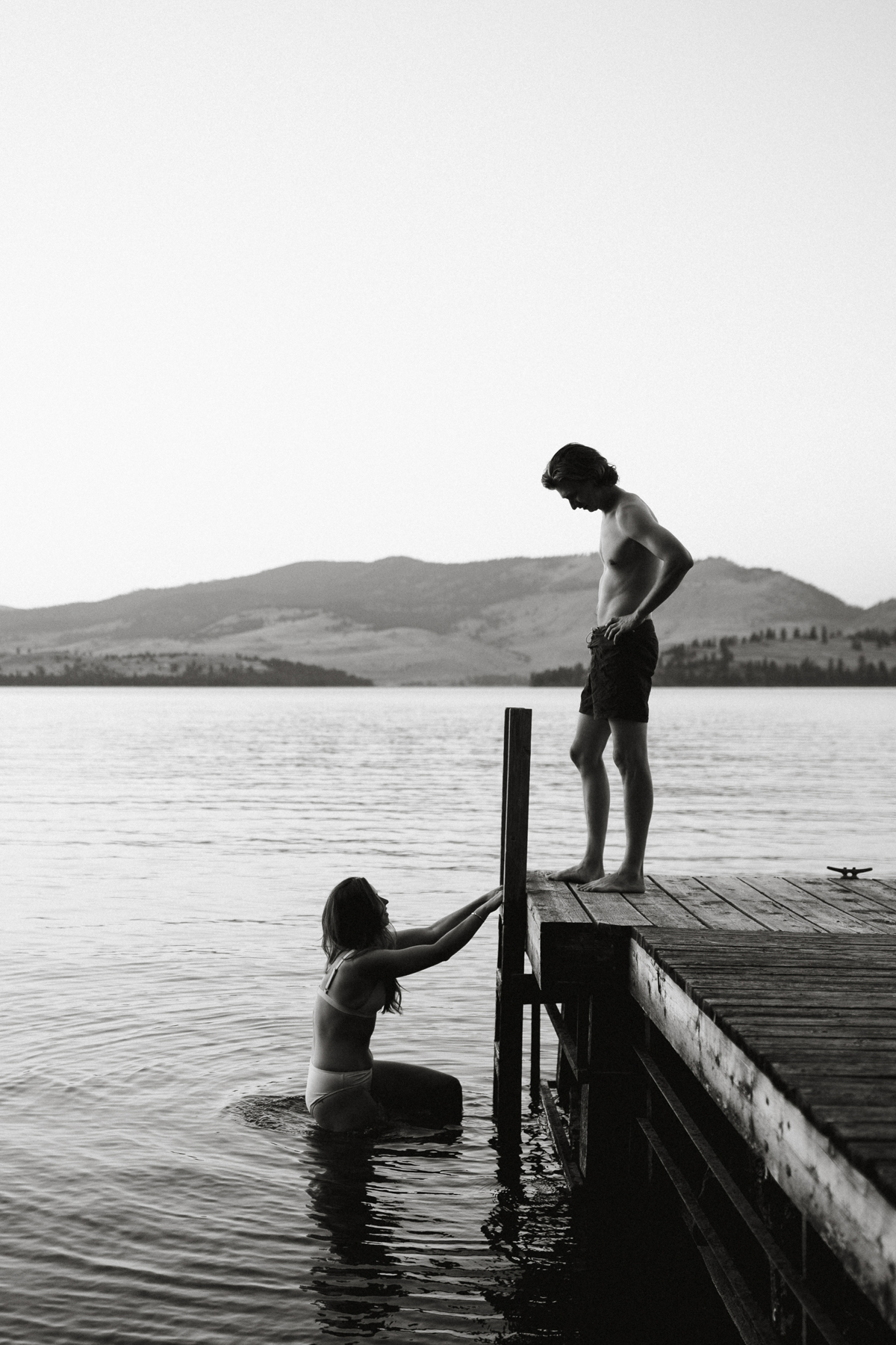 An engaged couple takes photos at a lake. 