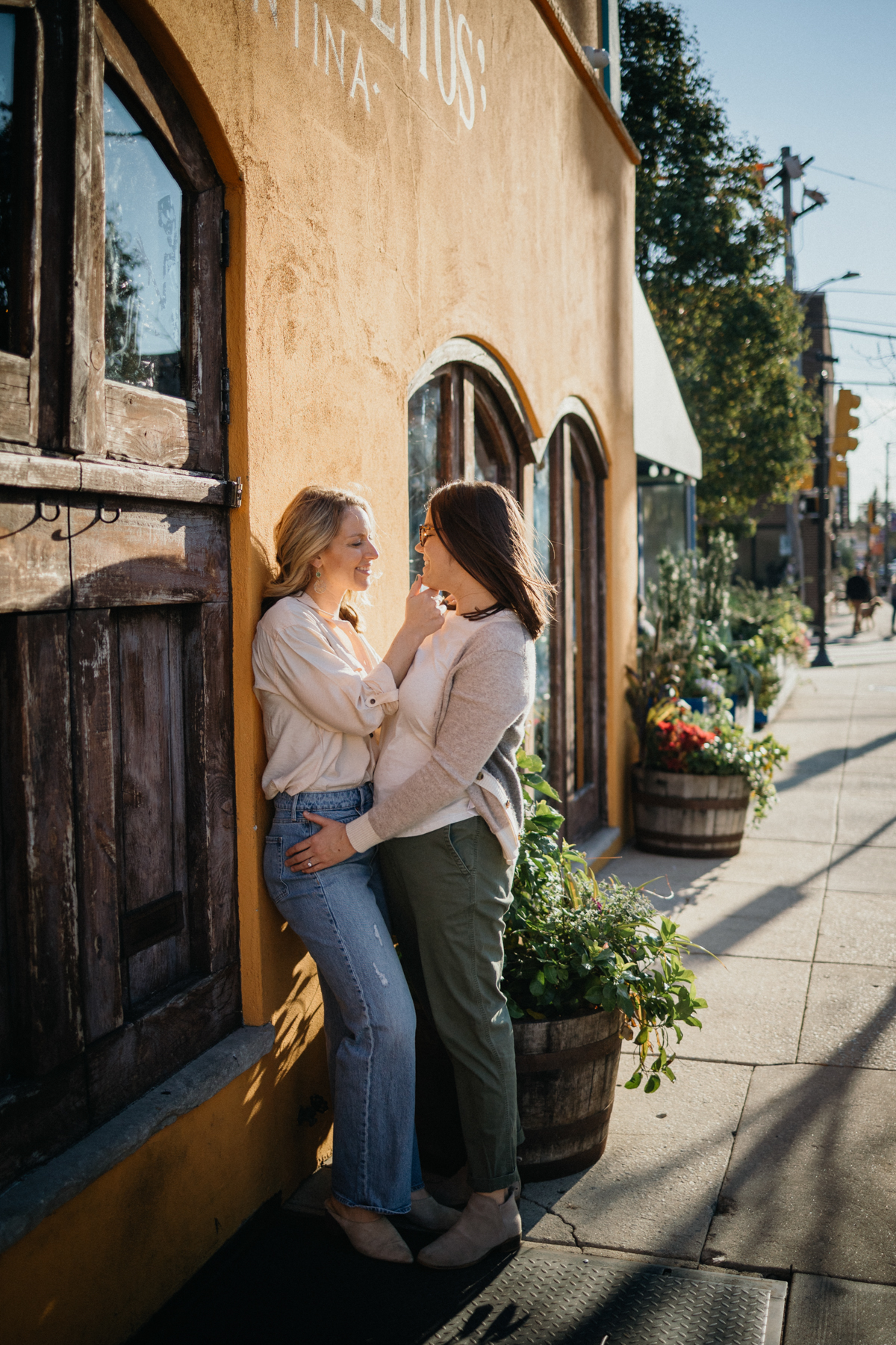 A couple leans against a wall, smiling and laughing together on a vibrant Philly street.