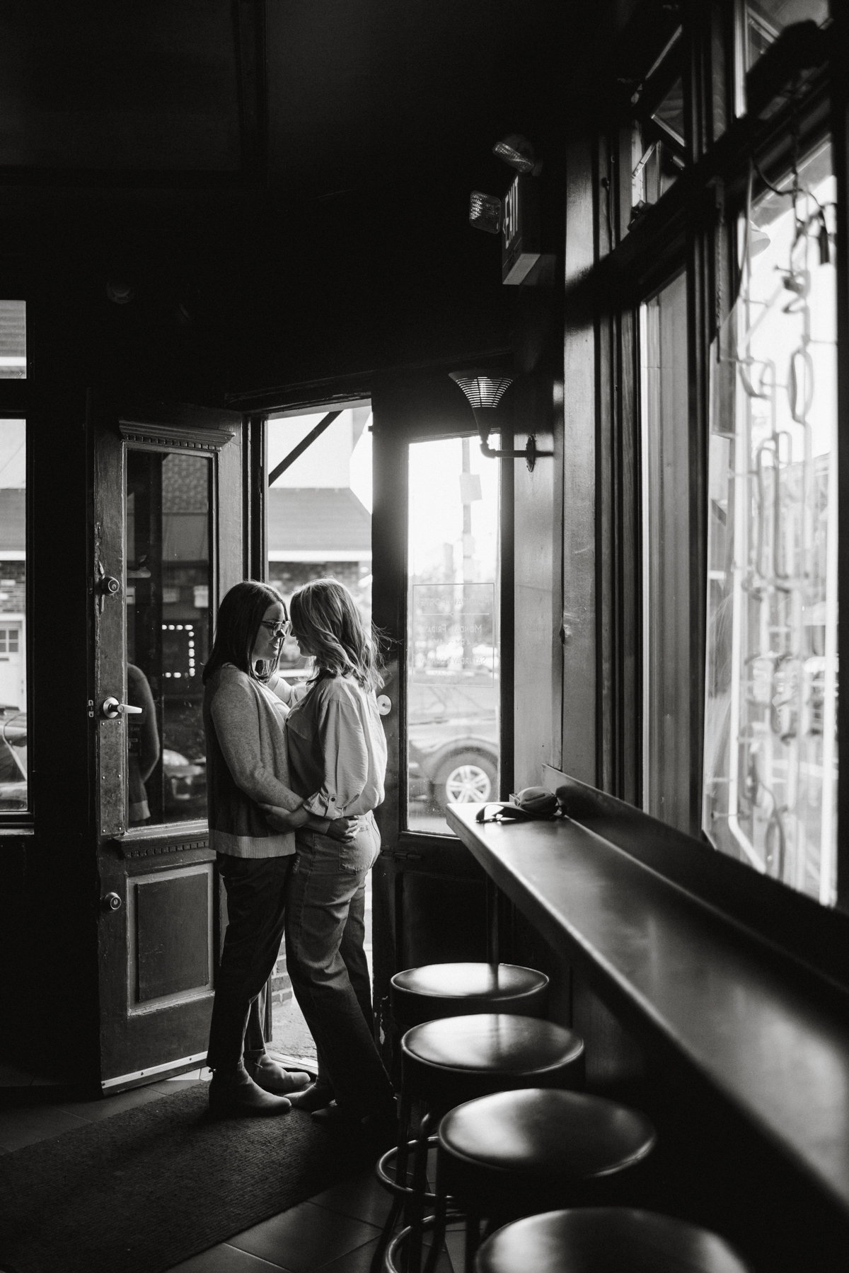 An lgbtq couple shares a toast at an industrial-style bar in Philly, with warm lighting and a laid-back vibe.