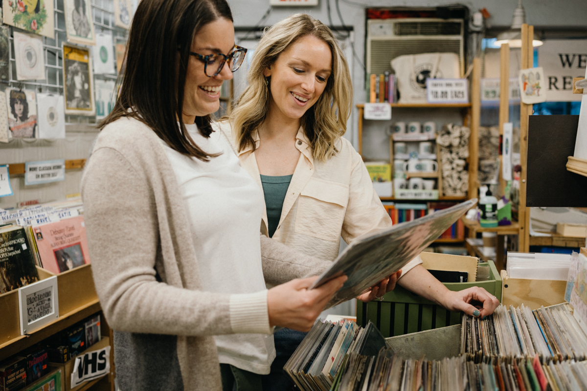 A couple browses through vinyl records in a cozy South Philadelphia record store, sharing a laugh.