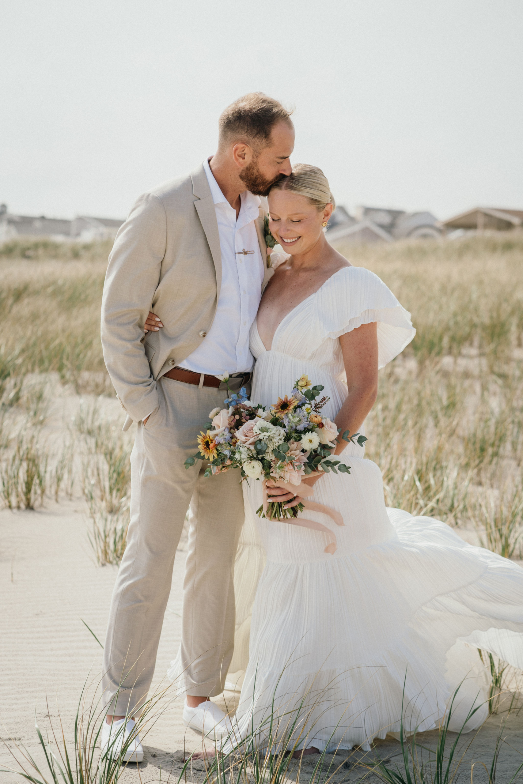 Wind tousling the couple’s hair during beach portraits before Deauville Inn wedding in Ocean City NJ. 