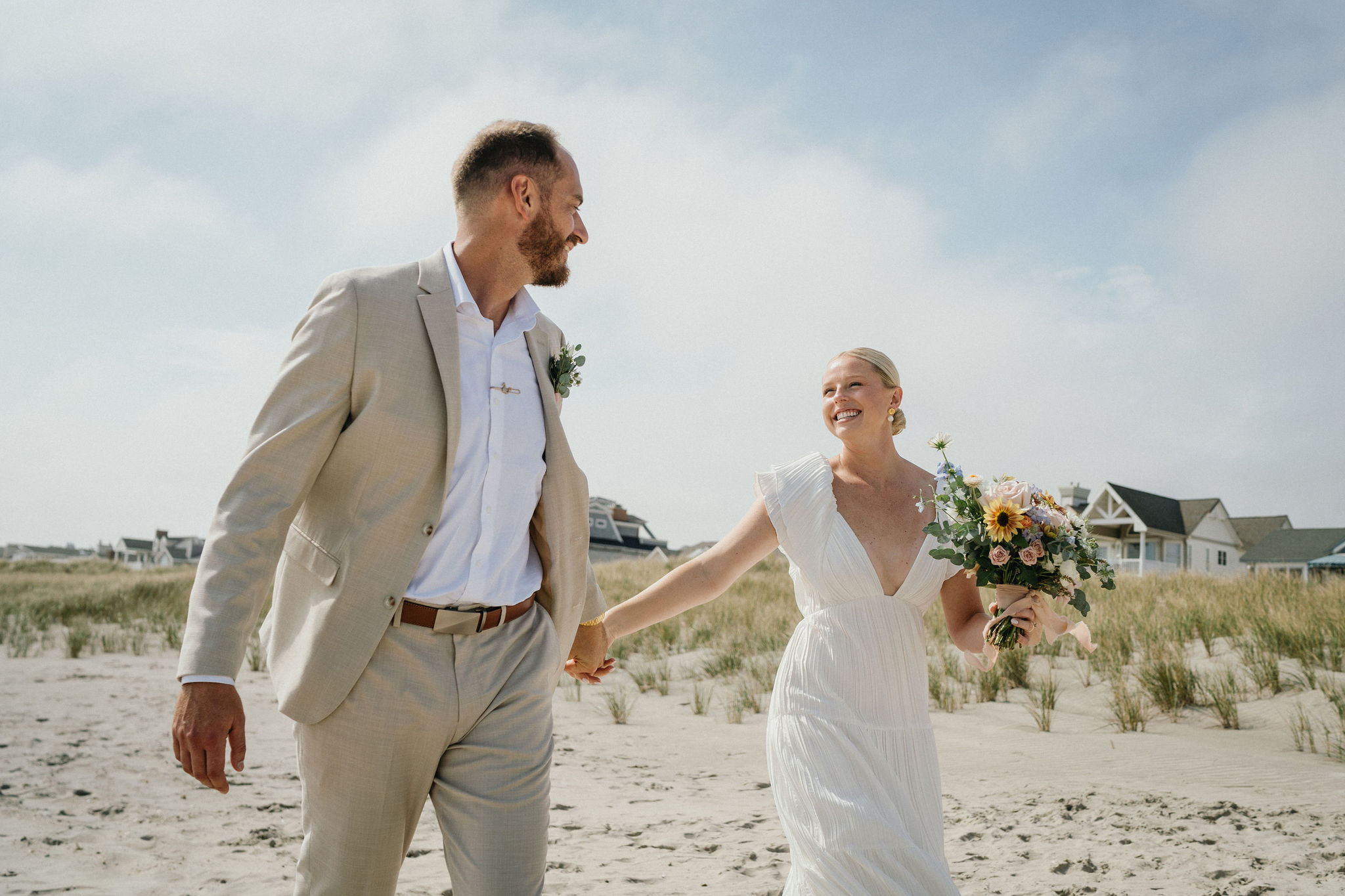 Newlyweds walking barefoot along the shoreline.