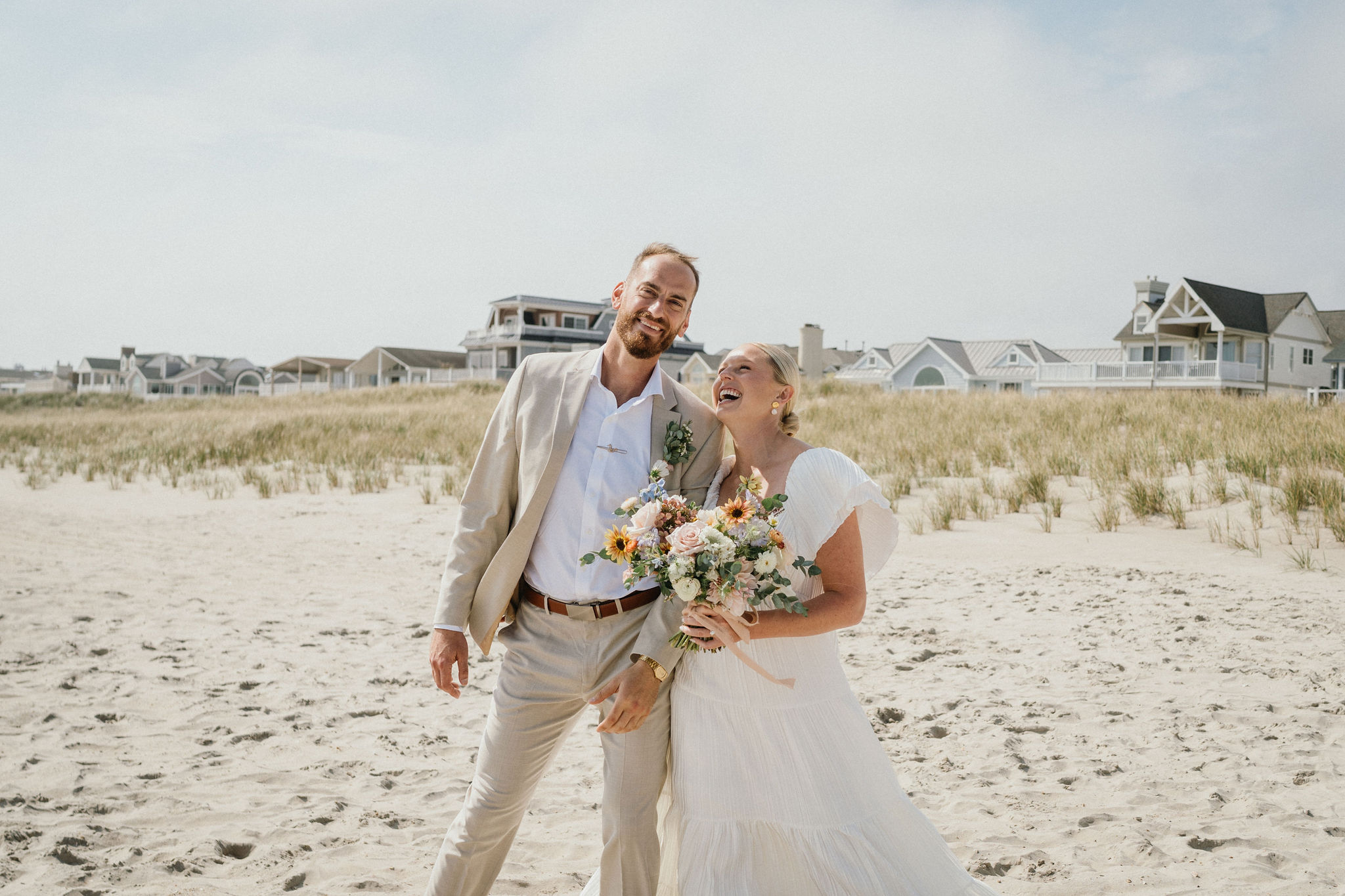 Bride’s dress flowing in the breeze on the beach.