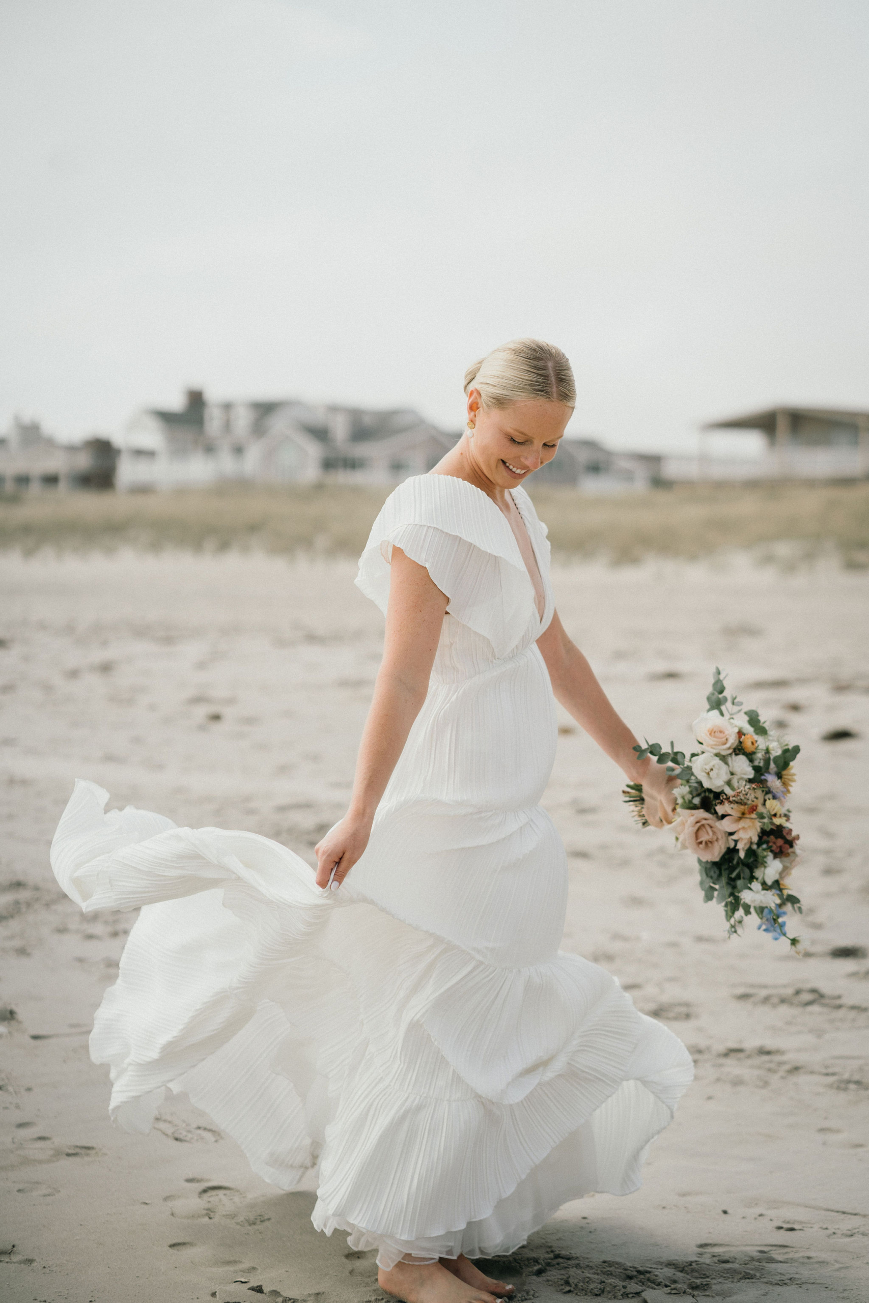 Bride spinning in her wedding dress on the dunes.