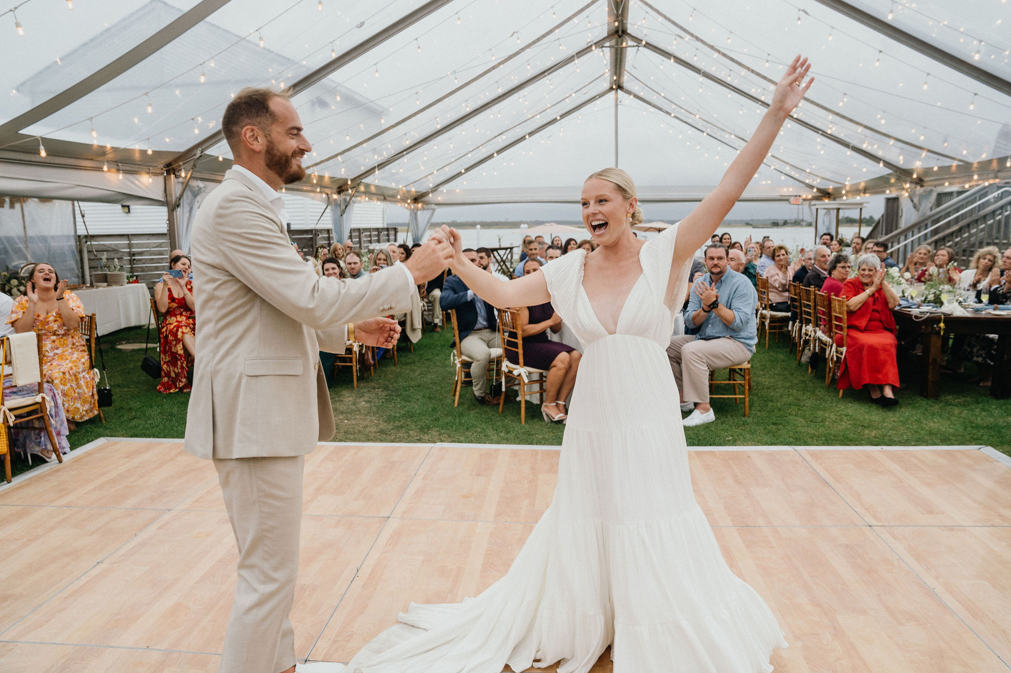 Cheers and laughter echo across the water as a couple shares their first dance at Deauville Inn wedding.