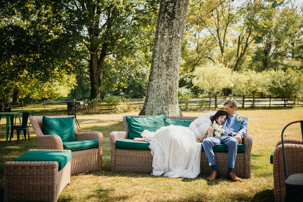 The bride leans on the groom’s shoulder, both smiling as the sun sets behind them.