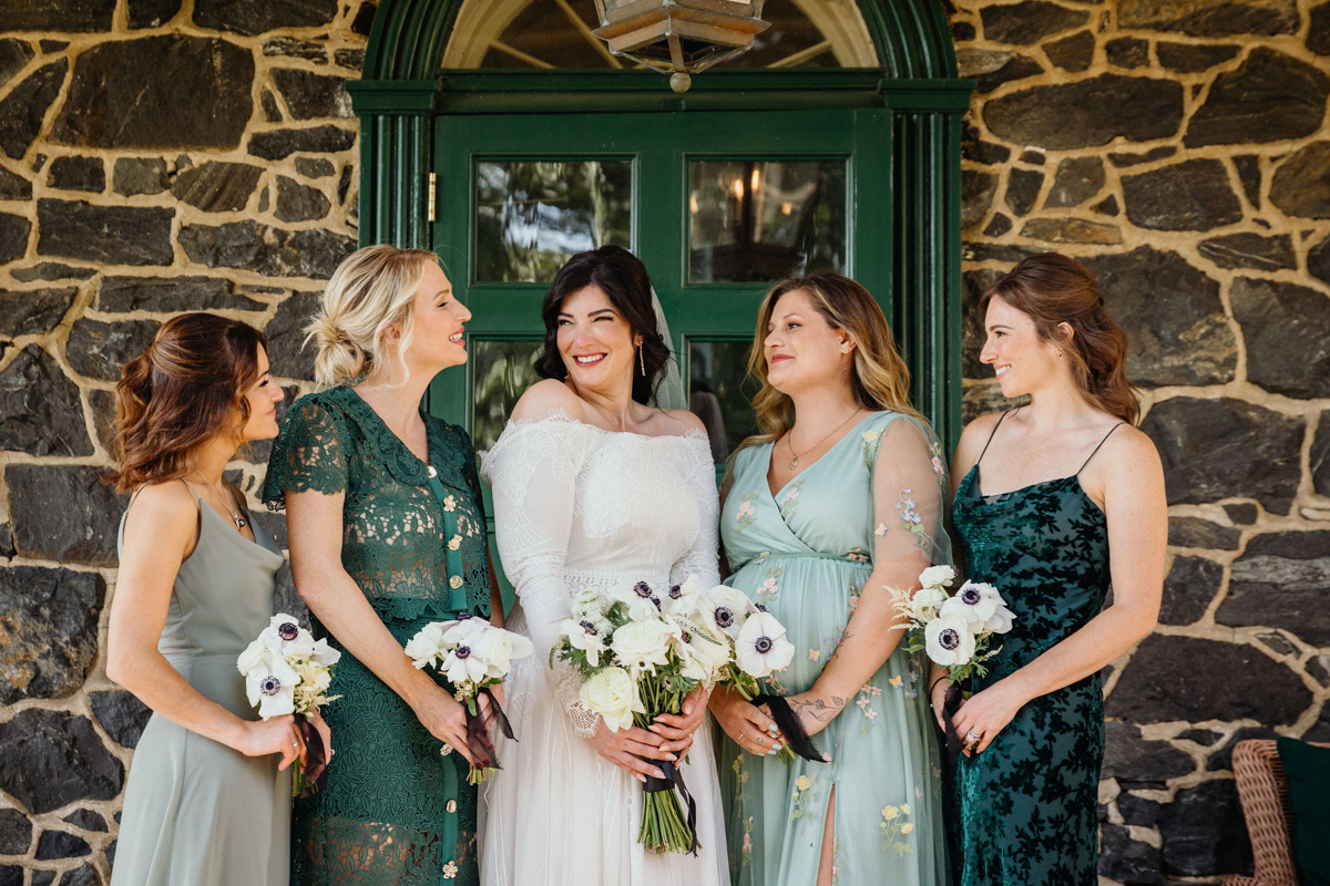 Bridesmaids in mismatched dresses laughing with the bride.