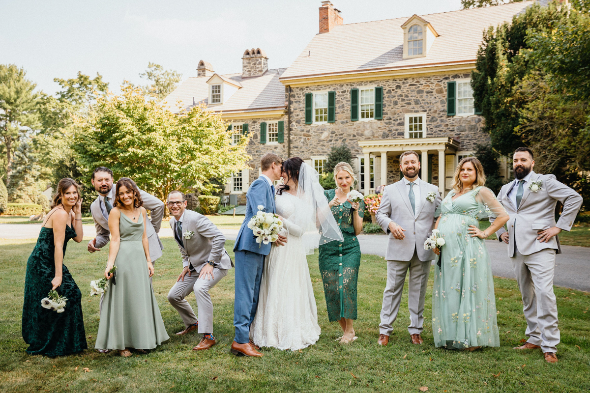 A joyful wedding party photo in front of the rustic barn at the Inn at Grace Winery.