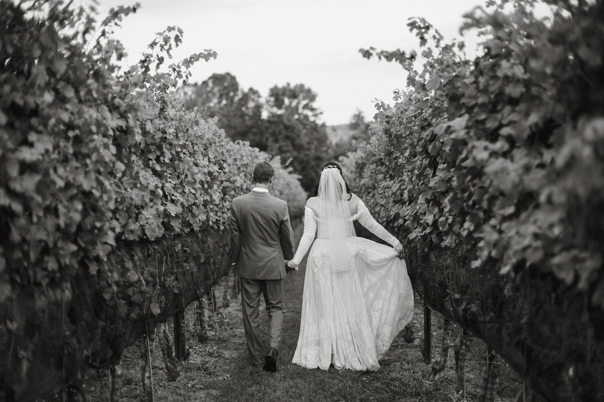 A gentle breeze rustles the vines as the couple walks hand in hand.