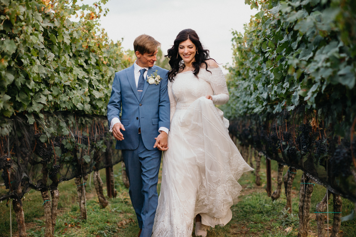 Carefree candid photo of couple running through vineyard.