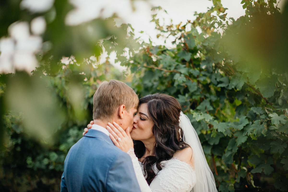 Couple embraces in private vineyard before wedding reception at Grace Winery.