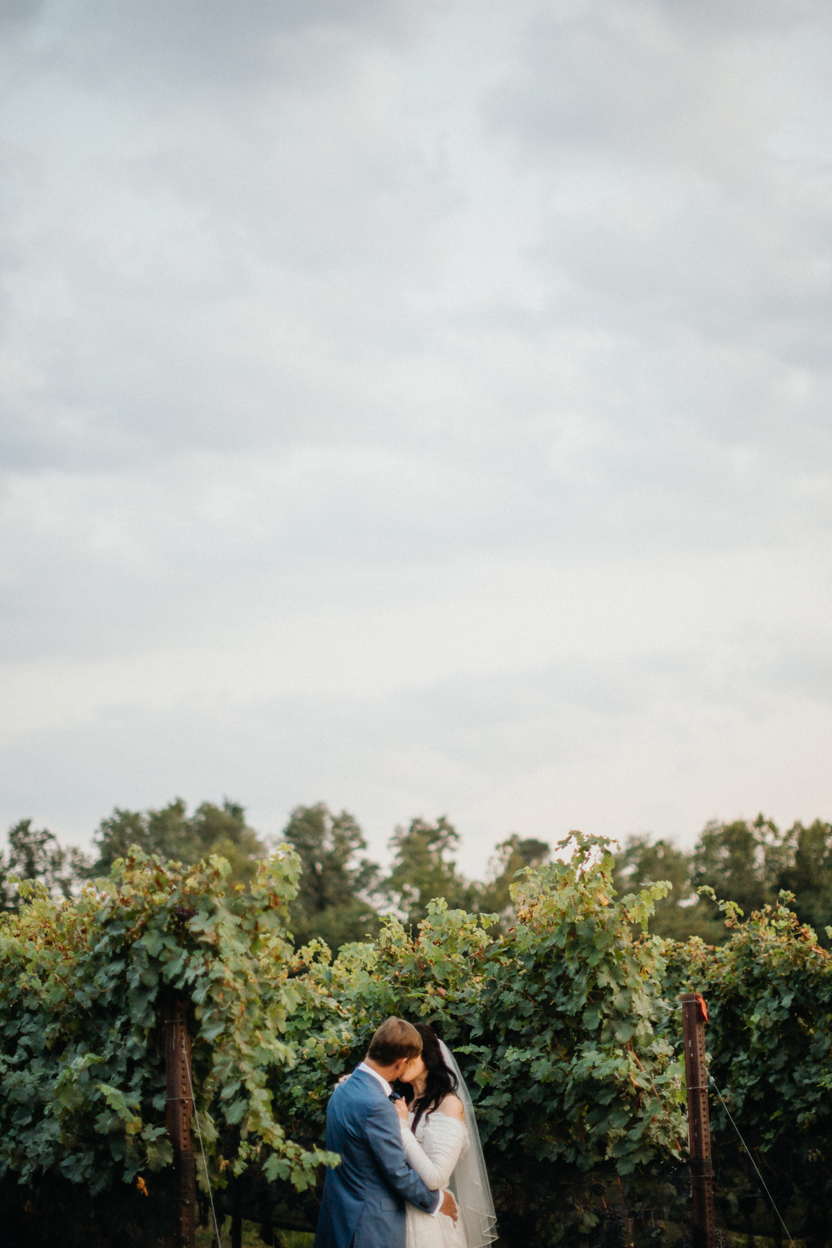 The bride and groom exchange vows in an intimate vineyard setting at Grace Winery wedding.