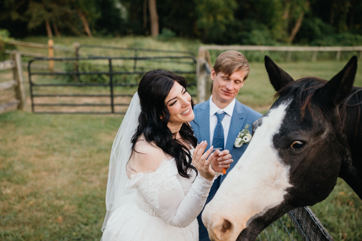 Candid photo of newlywed couple with horses at their Grace Winery wedding.