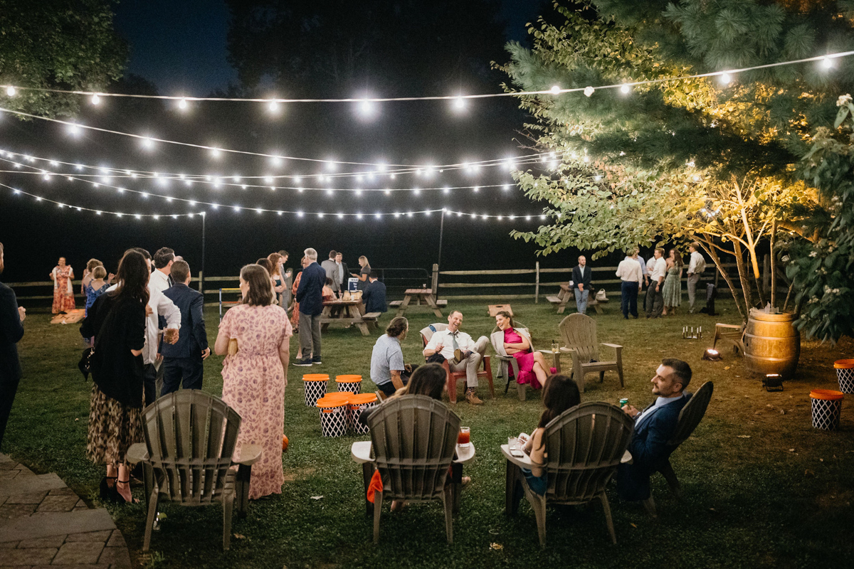 Guests enjoying an outdoor wedding reception with lawn games under string lights at Grace Winery wedding. 