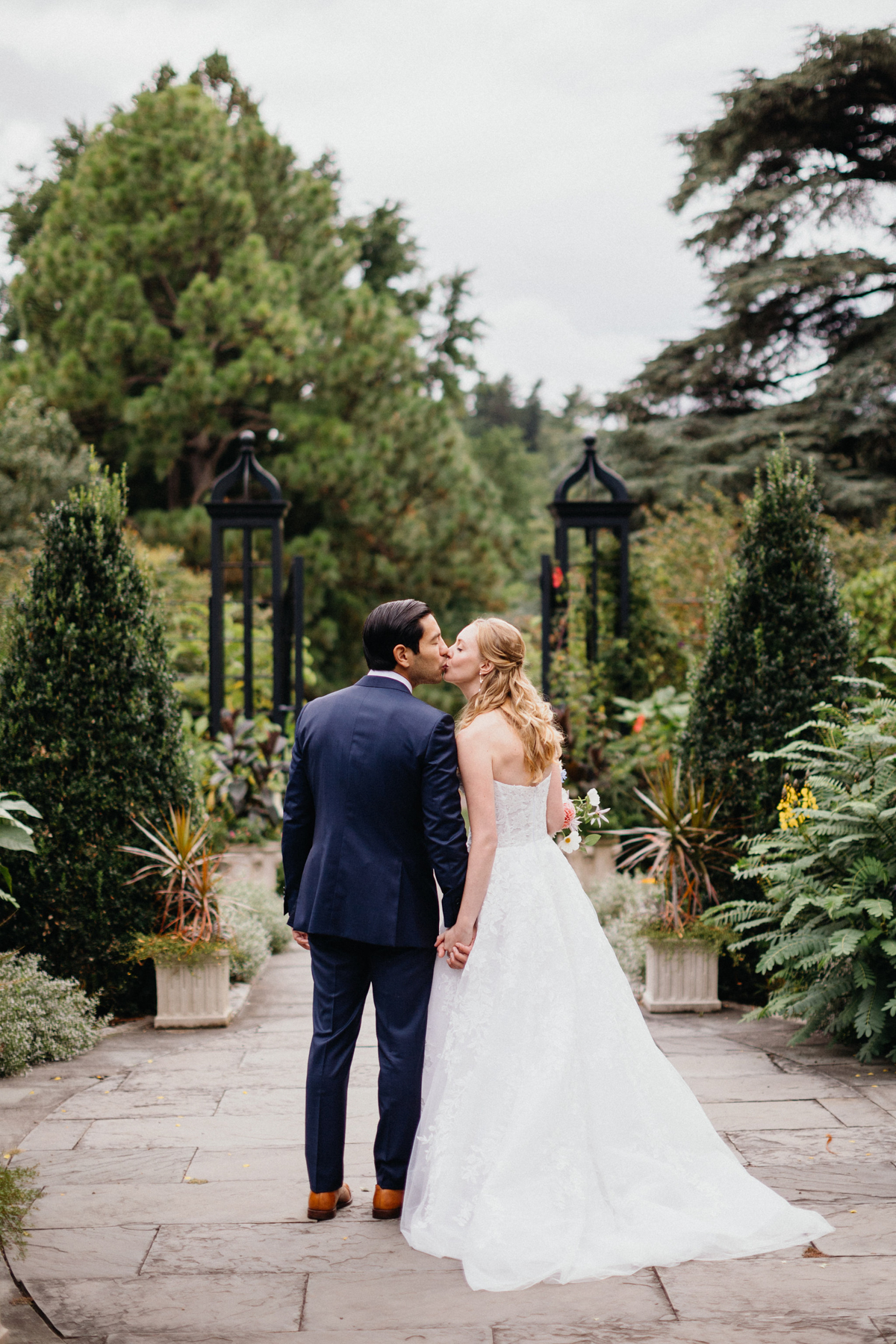 A joyful couple walking through a lush setting at a Morris Arboretum and Gardens wedding.