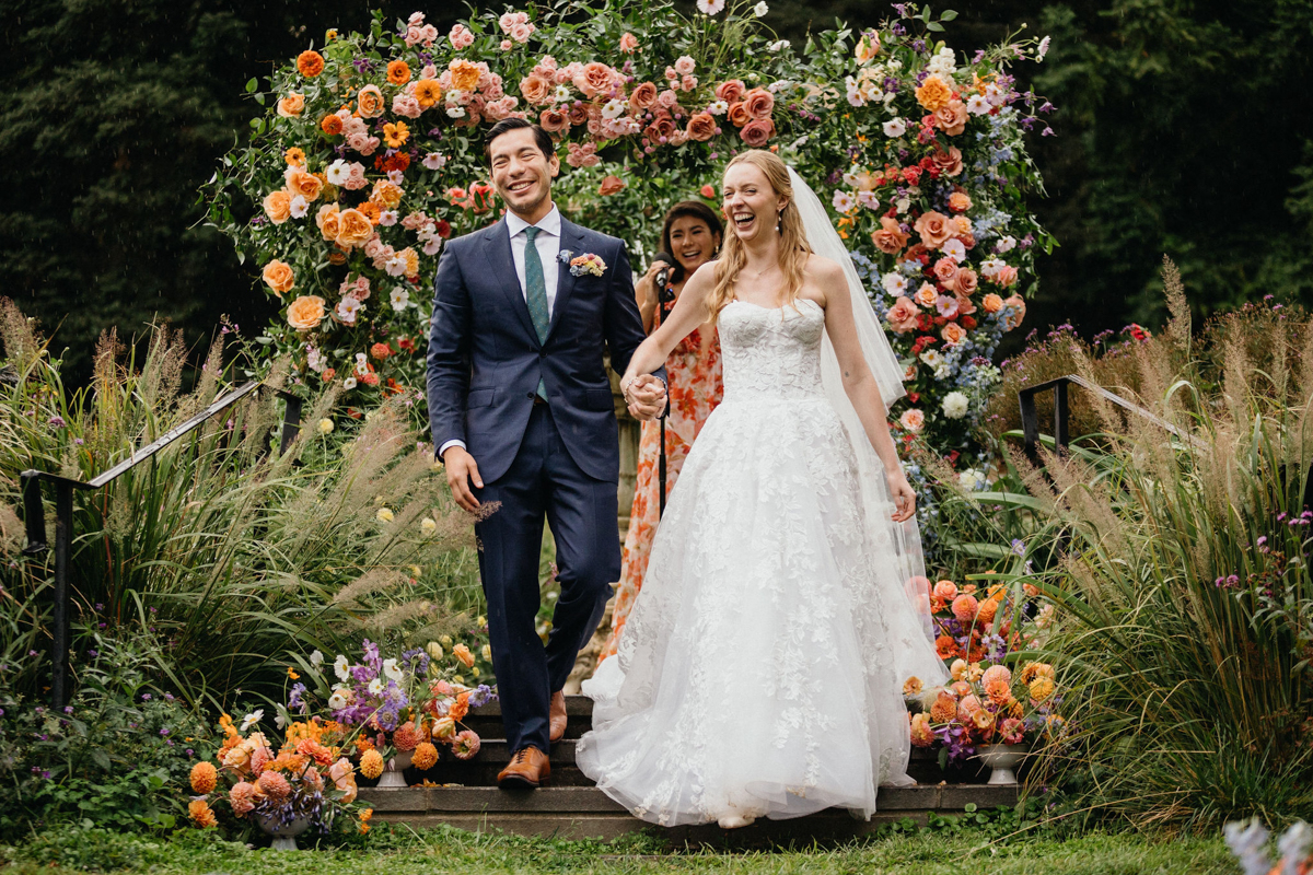 A newlywed couple walks hand in hand at their Morris Arboretum and Gardens wedding.