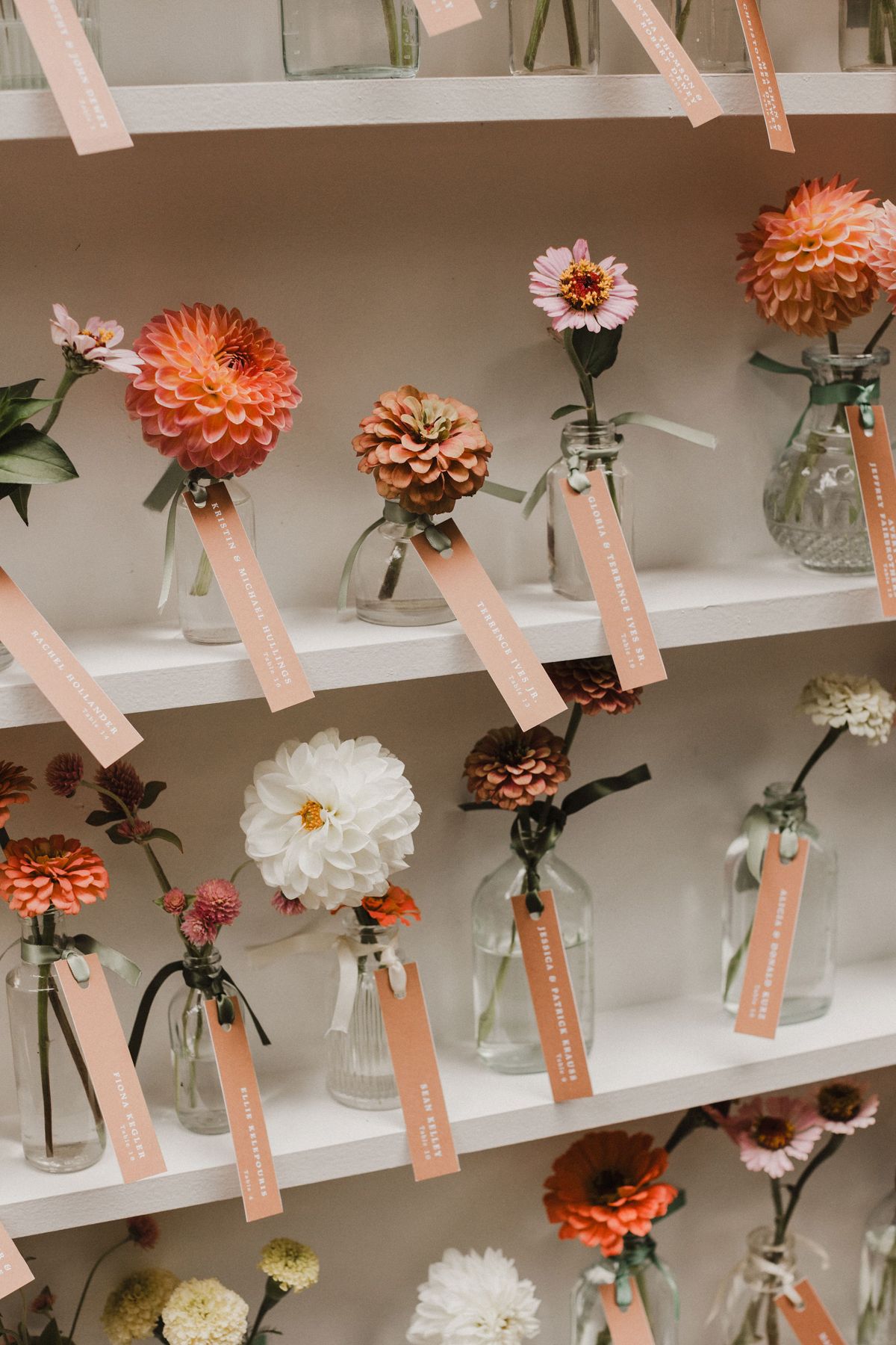 Modern wedding seating chart using bud vases and orange florals. 