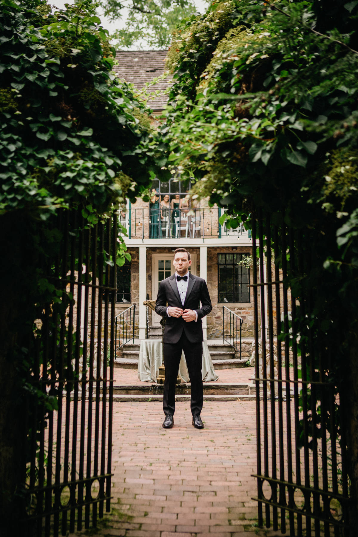 groom waiting to see his bride as bridesmaid watch out window