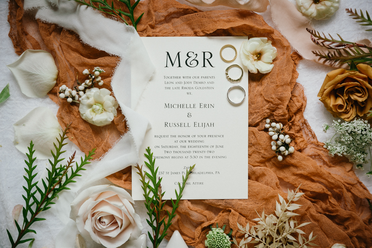 Flatlay of wedding details including invitation, florals, and rings – editorial photographer, Philadelphia wedding.