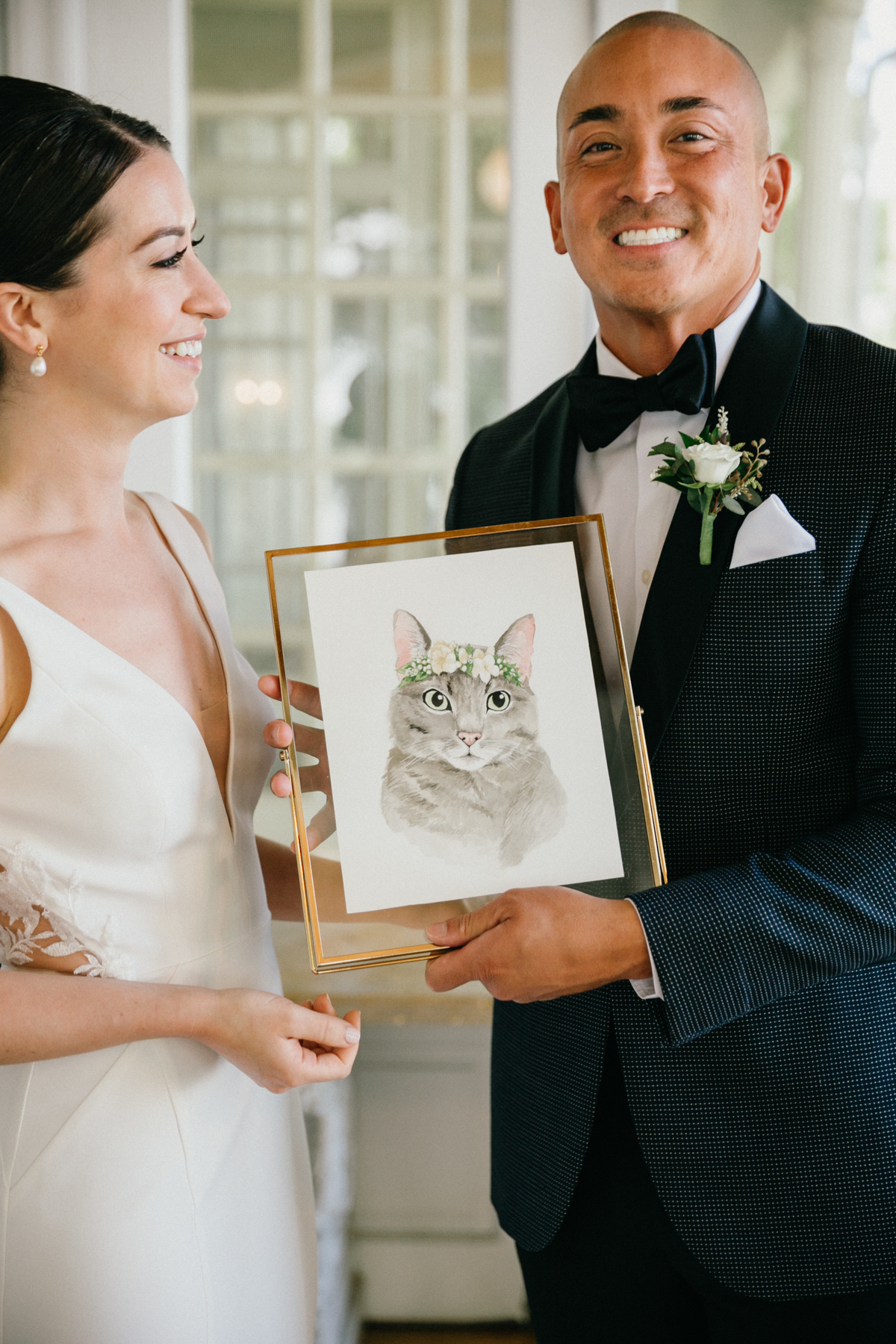 Groom holding painting of cat from bride during first look – documentary wedding photography