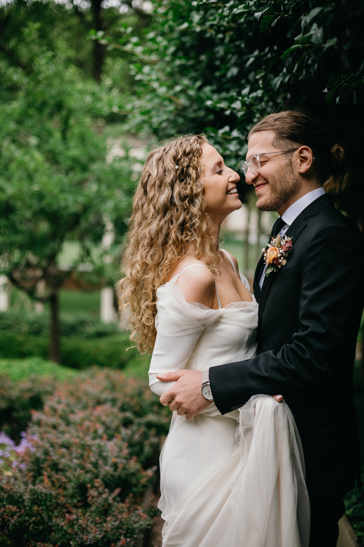 Natural, unscripted moment between the couple surrounded by spring blooms. – Candid photography, Philly wedding.