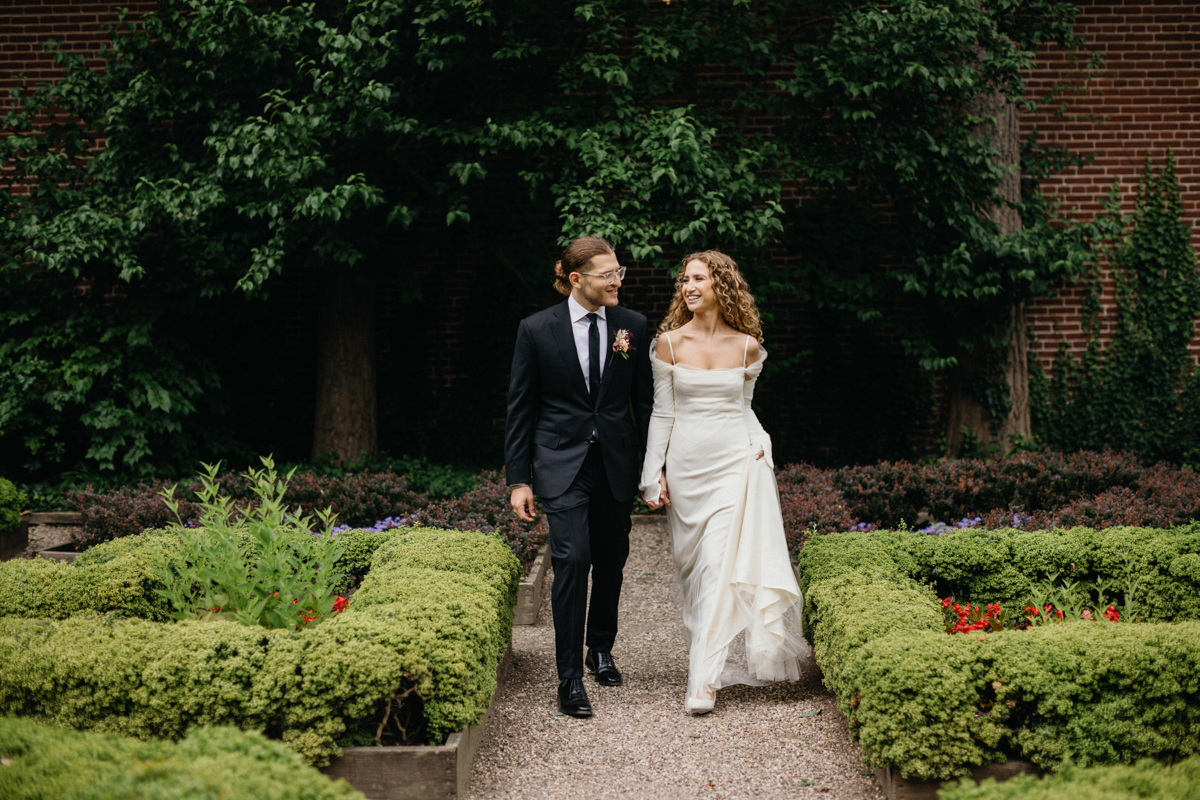 Playful portrait of the couple walking across the garden path. – Candid photography, Philly wedding.