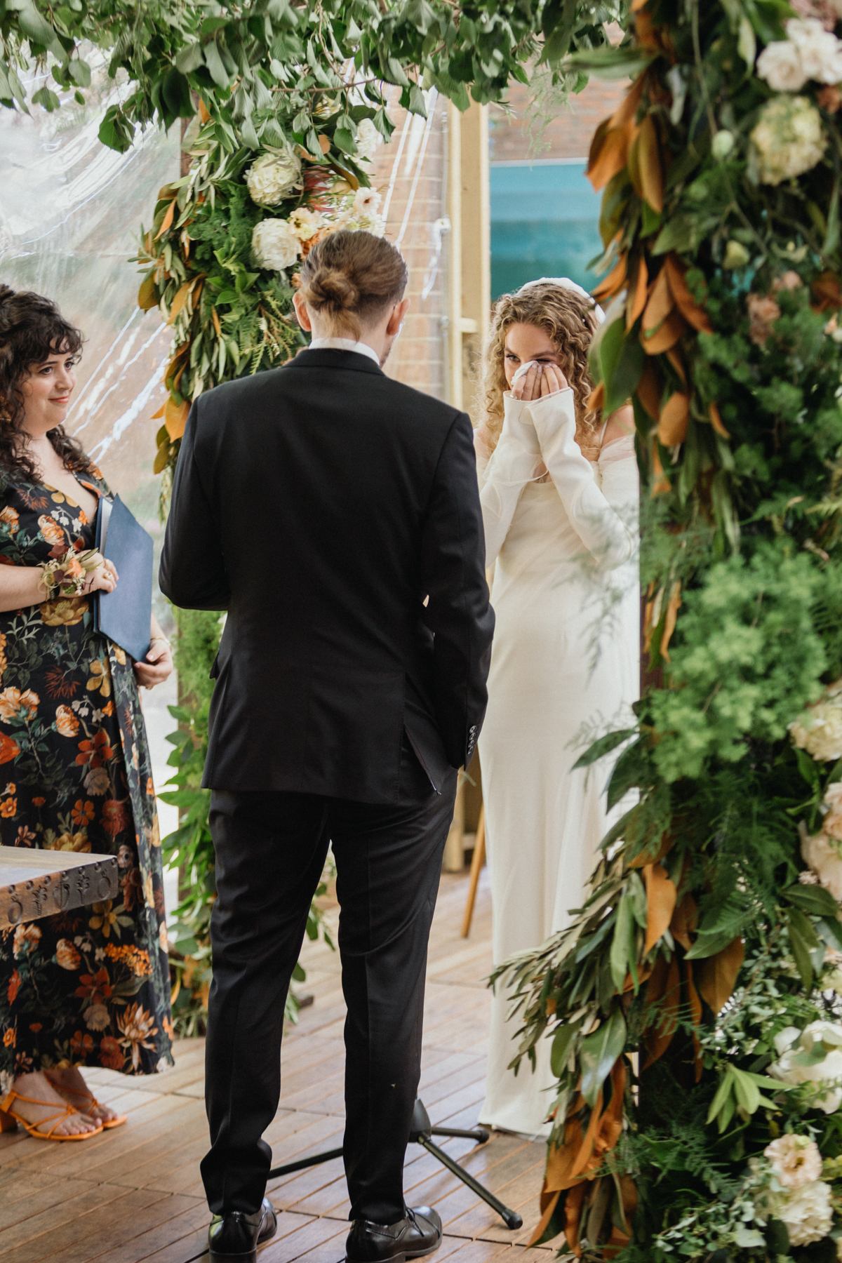 Couple exchanging vows under pastel florals – Philadelphia wedding photographer, candid photography