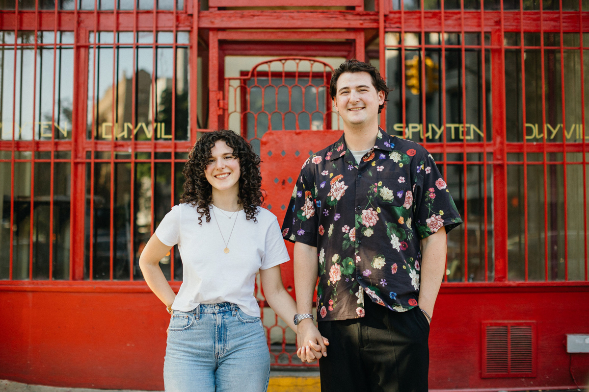 Brooklyn engagement session with a couple in front of a vibrant colored storefront.