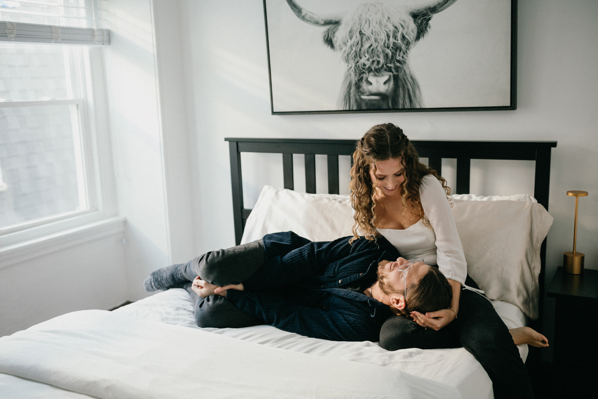 Home engagement photo of couple laying on the bed together