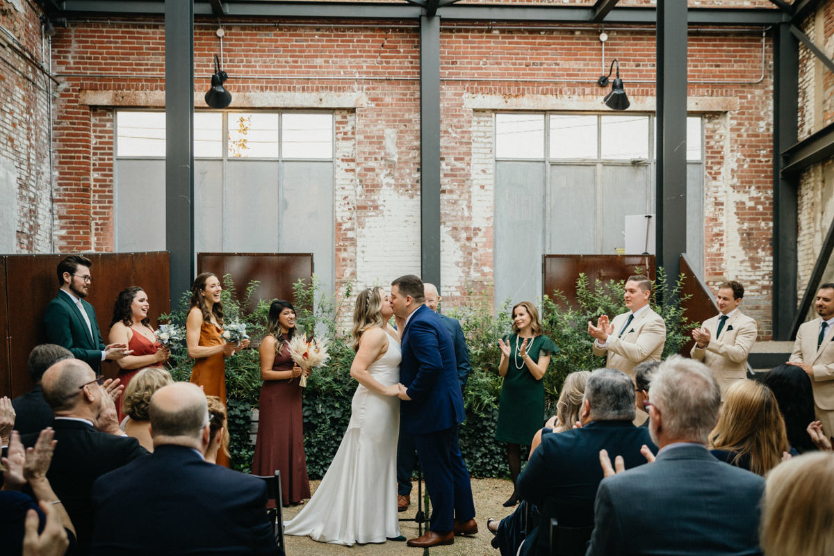 Wedding guests seated in mossy courtyard at Global Dye Works