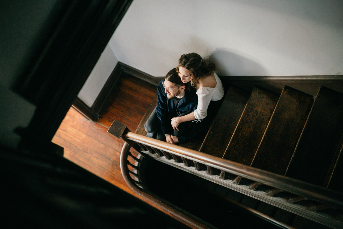 At home engagement photo of couple sitting together on the stairs
